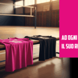 Due maglie da pallavolo, una rosa e una di colore diverso per il libero, poggiate su una panchina in palestra con il campo sullo sfondo.