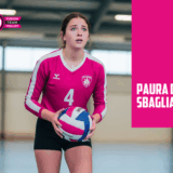 Adolescente giocatrice di pallavolo con un'espressione preoccupata tiene un pallone, con il testo "Paura di Sbagliare"